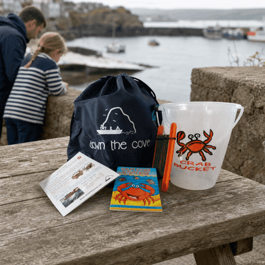 Standard crabbing kit with bucket, hand line and activity guide beside a Cornish harbour