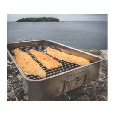 Salmon fillets being hot smoked outdoors in a stainless steel smoker