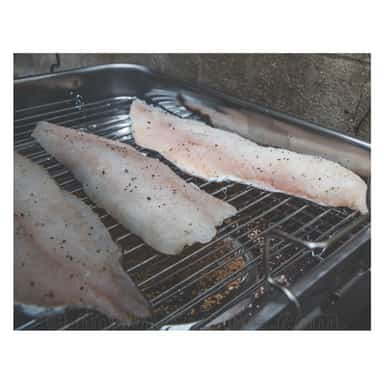 Fish fillets hot smoking inside a portable stainless steel smoker