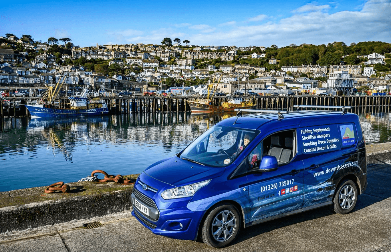 The Down The Cove blue van beside a Cornish harbour