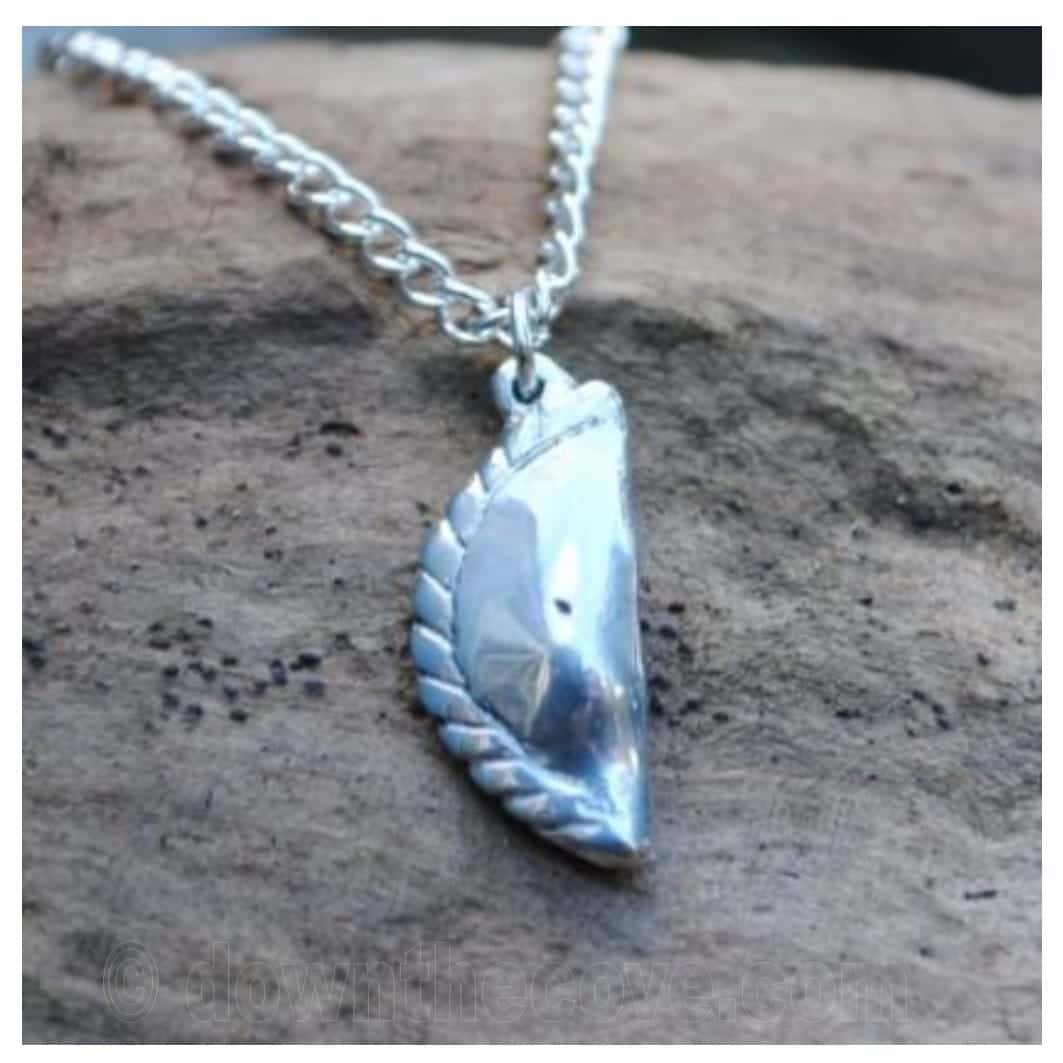 Cornish pasty pewter pendant on a silver curb chain, resting on a weathered piece of wood