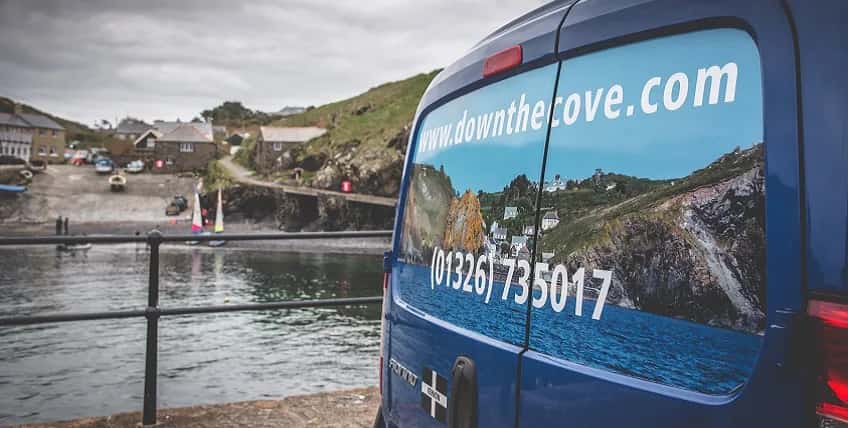 The Down The Cove blue van beside a Cornish harbour