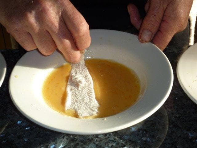 Dip the flour coated fish fillet in the lightly beaten egg.