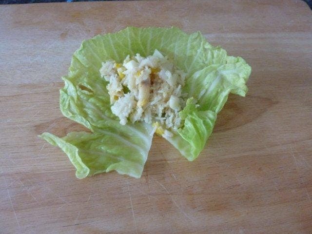 Lay a softened cabbage leaf onto a board and add a spoonful of the fish and rice mixture.